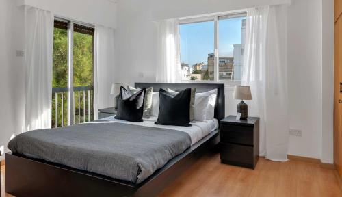 a bedroom with a bed and a large window at Phaedrus Living: Romanou Modern City Center Flat in Nicosia