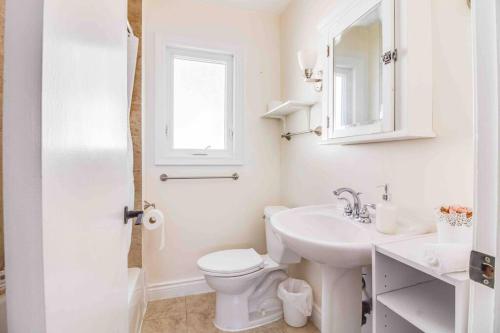 a white bathroom with a toilet and a sink at Beautiful house near bluffers beach, 25 minutes to Toronto Downtown, free parking, and wifi in Toronto