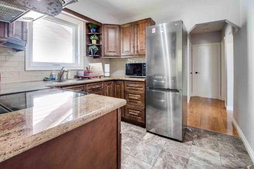 a kitchen with a stainless steel refrigerator and wooden cabinets at Beautiful house near bluffers beach, 25 minutes to Toronto Downtown, free parking, and wifi in Toronto