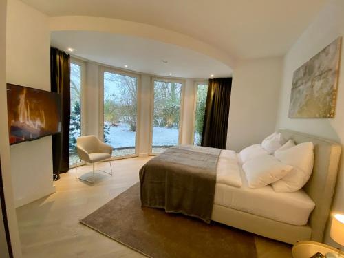 um quarto com uma cama, uma cadeira e janelas em Luxuriöse Villa zwischen Hannover und Hildesheim em Nordstemmen
