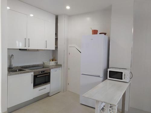 a white kitchen with a white refrigerator and a stool at Casablanca in Barbate