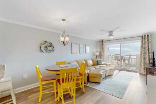a living room with a couch and a table and chairs at CAB03 Pelicans Penthouse in Oak Island