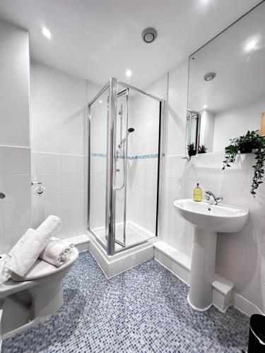 ein weißes Bad mit einer Dusche und einem Waschbecken in der Unterkunft Marsh House - 2 bedroom apartment in the Heart of the City in Bristol