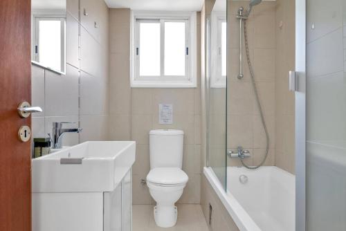 La salle de bains est pourvue de toilettes, d'un lavabo et d'une douche. dans l'établissement Phaedrus Living: Romanou Modern City Center Flat, à Nicosie