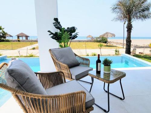 um pátio com cadeiras e uma mesa com uma garrafa de vinho em HERMOSA CASA CON PISCINA FRENTE AL MAR - PRIMERA FILA em Chincha Baja