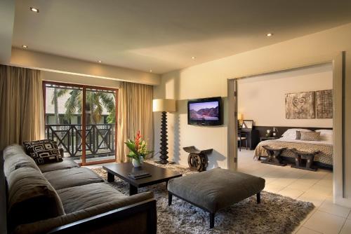 a living room with a couch and a bedroom at Labadi Beach Hotel in Accra