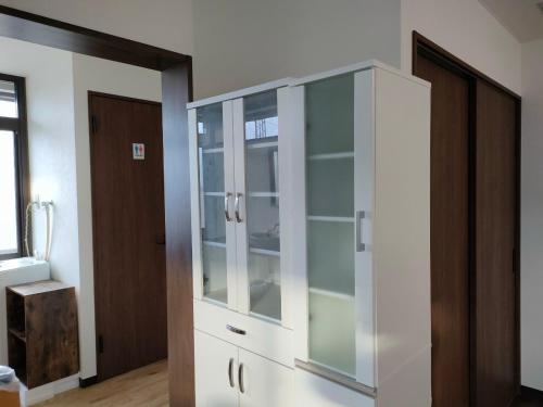 a white cabinet with glass doors in a room at 11月フルリフォーム 12月オープン恐竜一色ゲストハウスDinosaur Guesthouse in Katsuyama