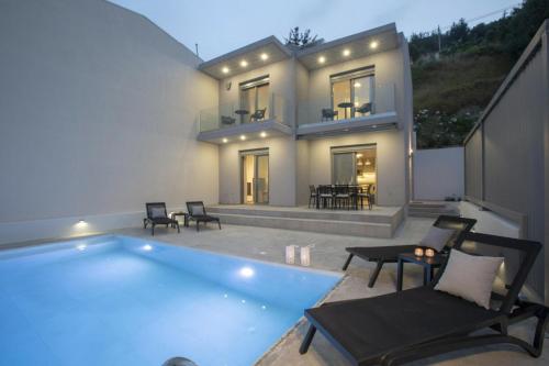 a house with a swimming pool in front of it at Aloft Luxury Villas with heated pool and sea view in Apolpaina