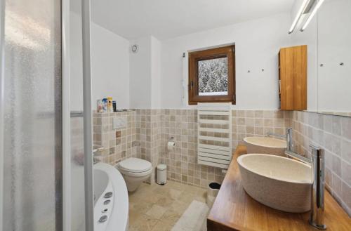 a bathroom with two sinks a toilet and a shower at Magnificent flat in Crans-Montana - 856 in Crans-Montana
