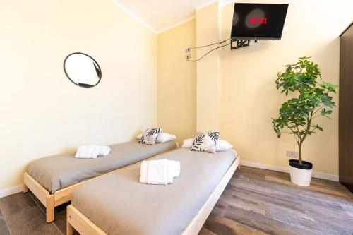 two beds in a room with a tv on the wall at Appartamenti Vista Mole, Centro a 15 min - Luxury Suites & fast WiFi in Turin