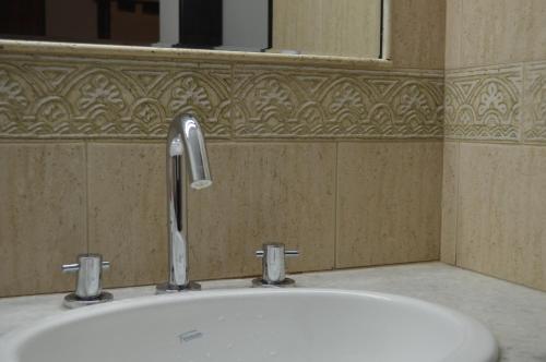 ein Waschbecken mit einem Wasserhahn und einem Spiegel in der Unterkunft Hotel Posta Arroyito in Arroyito Challacó