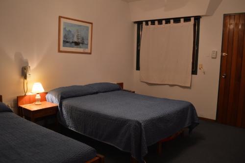 ein Hotelzimmer mit 2 Betten und einer Lampe auf dem Tisch in der Unterkunft Hotel Posta Arroyito in Arroyito Challacó