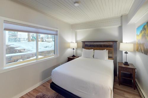 a bedroom with a white bed and a window at Dulany at the Gondola in Steamboat Springs