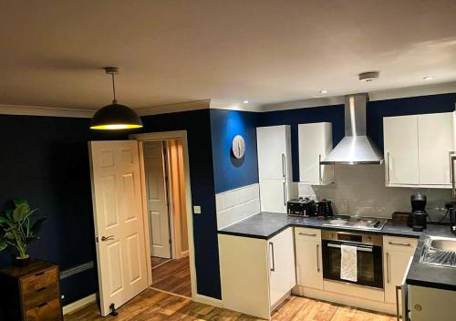 una cucina con armadi bianchi e parete blu di Chic Coastal Hideaway: 2-BR Gem Southend Stays a Southend-on-Sea