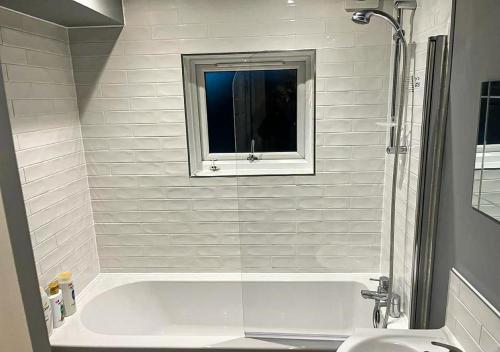 a white bath tub with a window in a bathroom at Chic Coastal Hideaway: 2-BR Gem Southend Stays in Southend-on-Sea