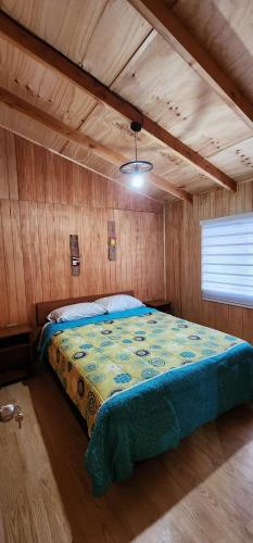 1 dormitorio con 1 cama en una habitación de madera en Entre Esteros Hornopiren, en Hornopirén