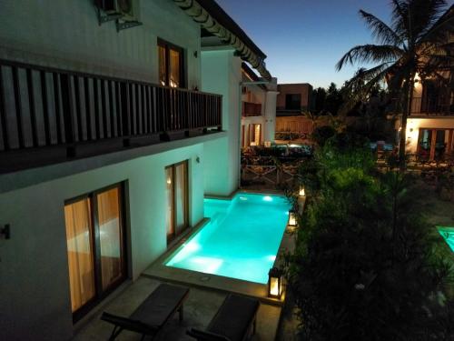 - une piscine en face d'une maison la nuit dans l'établissement Natural Park Villa Resort, à Pingwe