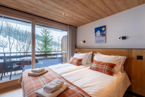 a bedroom with a large bed and a large window at TARDEVANT 21 in Le Grand-Bornand