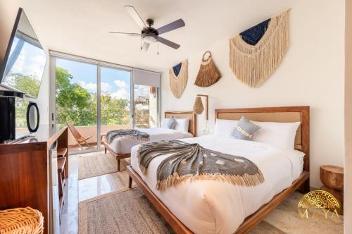 トゥルムにあるNHOA 307A Lux 2BR Condo Pool View in Aldea Zamaのベッド2台と天井ファン付きの寝室