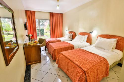 ein Hotelzimmer mit 2 Betten mit orangefarbener Bettwäsche in der Unterkunft Complexe El Bassatine in Beni Mellal
