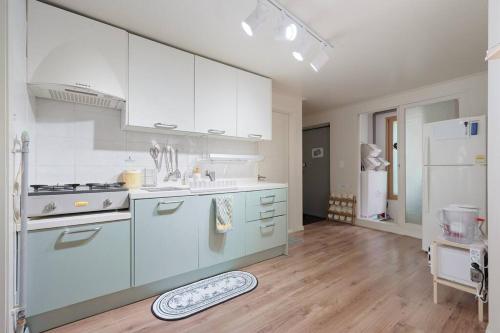 a kitchen with white cabinets and a wooden floor at Seoul Sensibility B&B House in Seoul