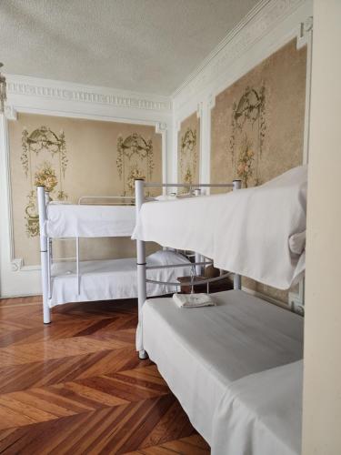 two white bunk beds in a room with wooden floors at Anys Hostal in Mexico City