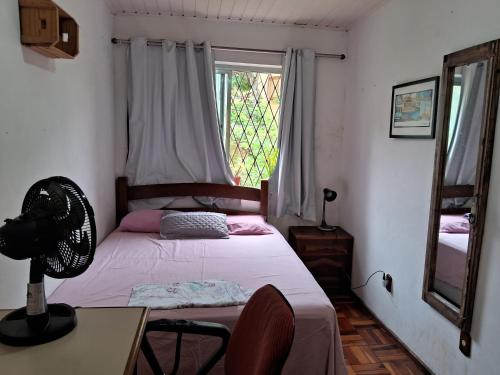 a bedroom with a bed and a desk and a window at Os fora de casa Hostel in Porto Alegre