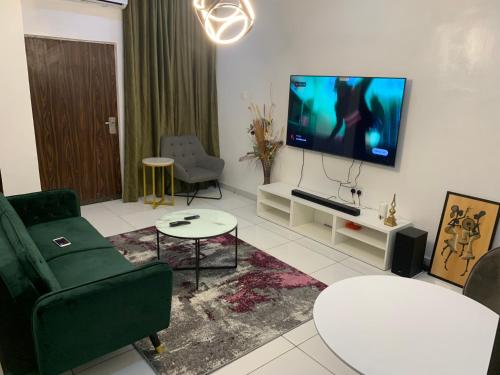 een woonkamer met een bank en een tv aan de muur bij Luxury apartments in Ibadan