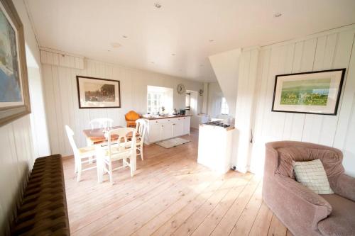 a living room with a table and chairs and a kitchen at The Lodge: Adorable, Romantic Thatched Cottage in Freshwater