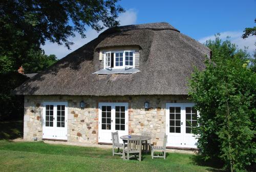 an old stone house with a thatched roof and a table at The Lodge: Adorable, Romantic Thatched Cottage in Freshwater