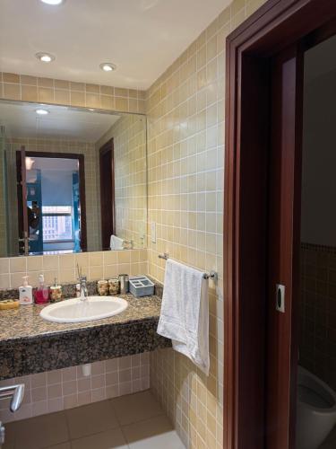 uma casa de banho com um lavatório e um espelho em Living Room JBR no Dubai