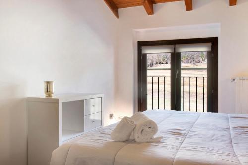- une chambre blanche avec un lit et des serviettes dans l'établissement Relax Tra Monti e Laghi, à Brenta