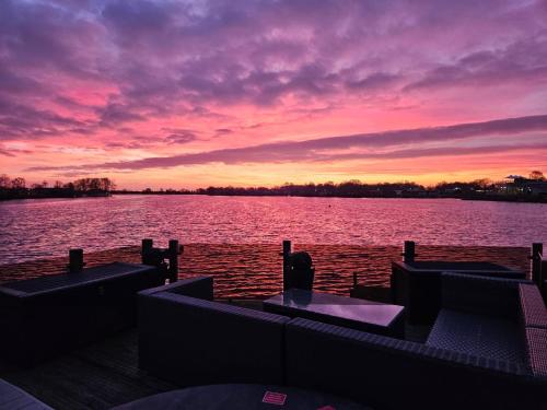 a sunset on a dock on a body of water at Lake View with Private Hot Tub at Tattershall Lakes in Tattershall