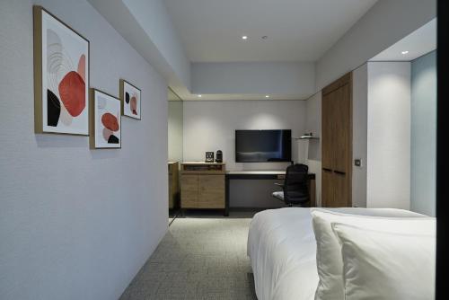 a bedroom with a bed and a desk with a television at K Hotel Taipei Nanjing in Taipei