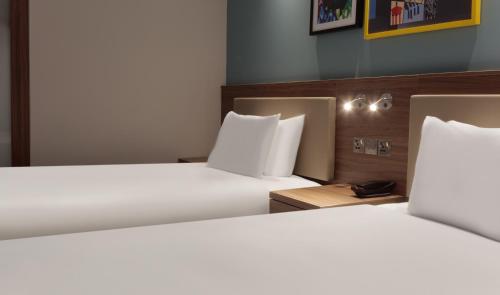 two beds in a hotel room with white sheets and pillows at Hampton By Hilton Edinburgh Airport in Ingliston