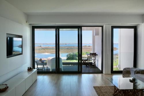a living room with sliding glass doors with a view at Del Mar Village, Apartment T1 , Açor in Fuzeta