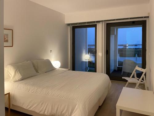 a bedroom with a white bed and a balcony at Del Mar Village, Apartment T1 , Açor in Fuzeta