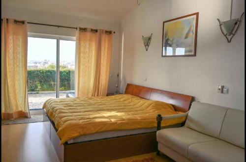 um quarto com uma cama, um sofá e uma janela em Monte Ponto em Lagos