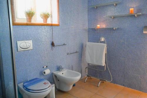 uma casa de banho em azulejos azuis com um WC e um lavatório em Monte Ponto em Lagos
