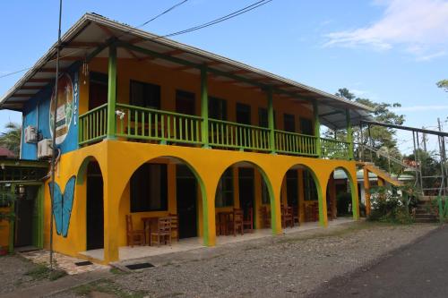 a yellow and green building with tables and chairs at Cool & Calm Hotel in Manzanillo