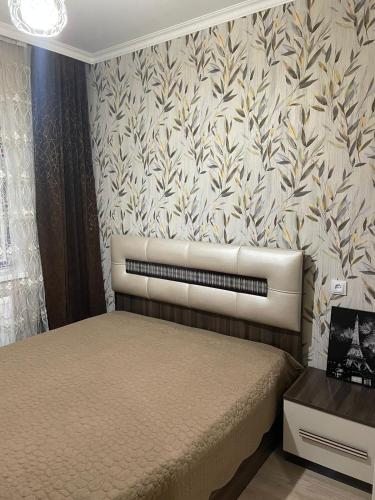 1 dormitorio con cama y papel pintado con motivos florales en Aldaga, en Tiflis