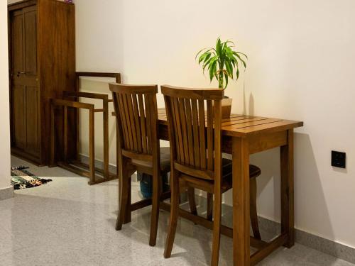 uma mesa de madeira com duas cadeiras e um vaso de plantas em Golden Wave em Ahangama