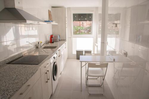 a white kitchen with a sink and a table at Verarlanza in Lerma