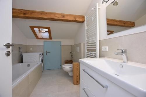 a bathroom with a tub and a toilet and a sink at FeWo Löwenzahn, Oberstaufen/Wiedemannsdorf in Oberstaufen