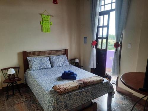 una camera da letto con un letto con un cappello blu sopra di Pousada Residência Balestra a Tiradentes