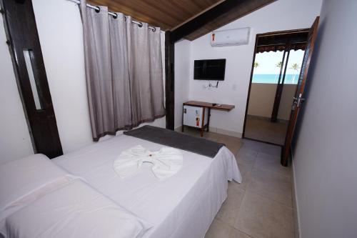 Schlafzimmer mit einem weißen Bett und einem TV in der Unterkunft Pousada Girassol in Maceió