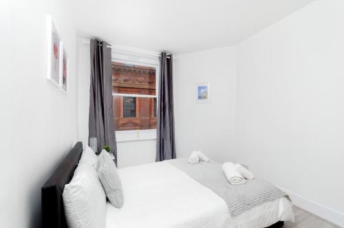 a white bedroom with a bed and a window at Covent Garden Central Apartments in London