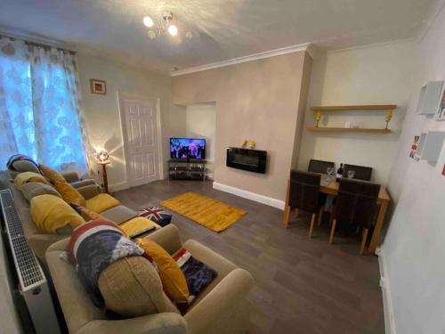 a living room with a couch and a dining room at East Stay 2/3 bedroom Flat in Westoe