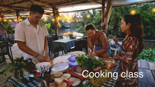 a group of people standing around a table preparing food at Song Ngư Riverside Homestay in Can Tho