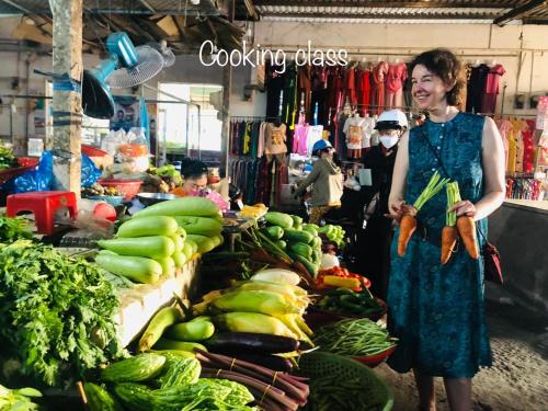 a woman is standing in a market with vegetables at Song Ngư Riverside Homestay in Can Tho
